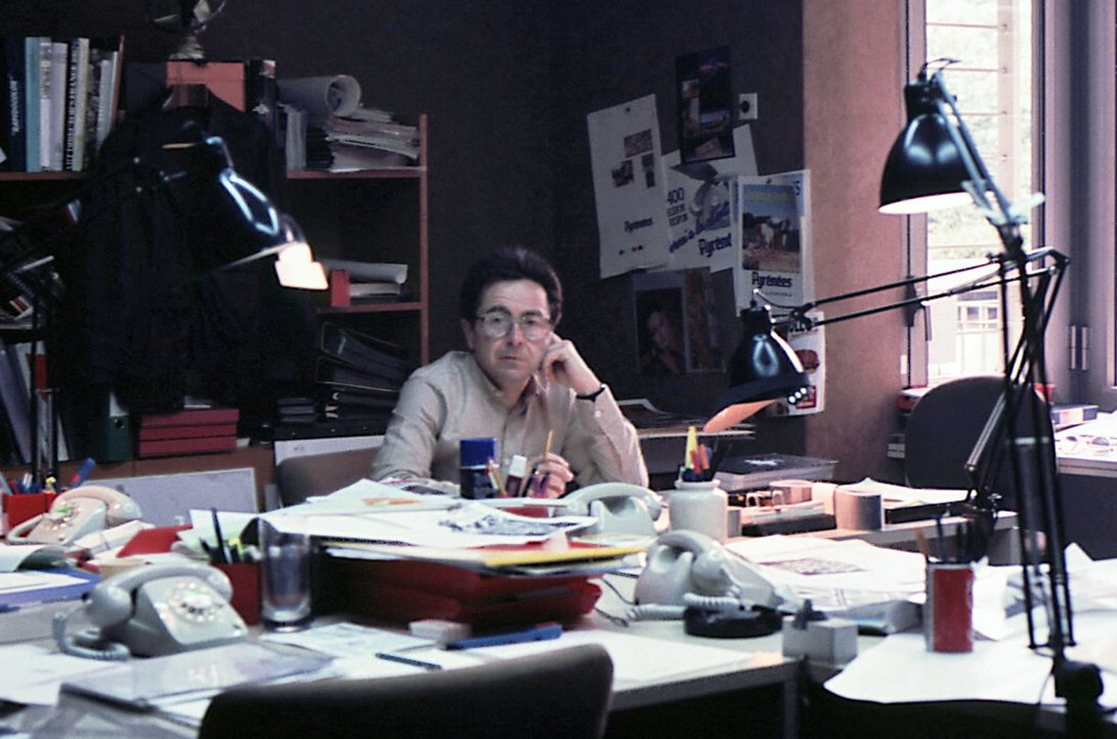 José Luis Gimeno en su mesa del estudio de Cid Publicidad en Paseo de Gracia, Barcelona, rodeado de teléfonos de disco, flexos, bocetos y carteles de la campaña Pyrénées