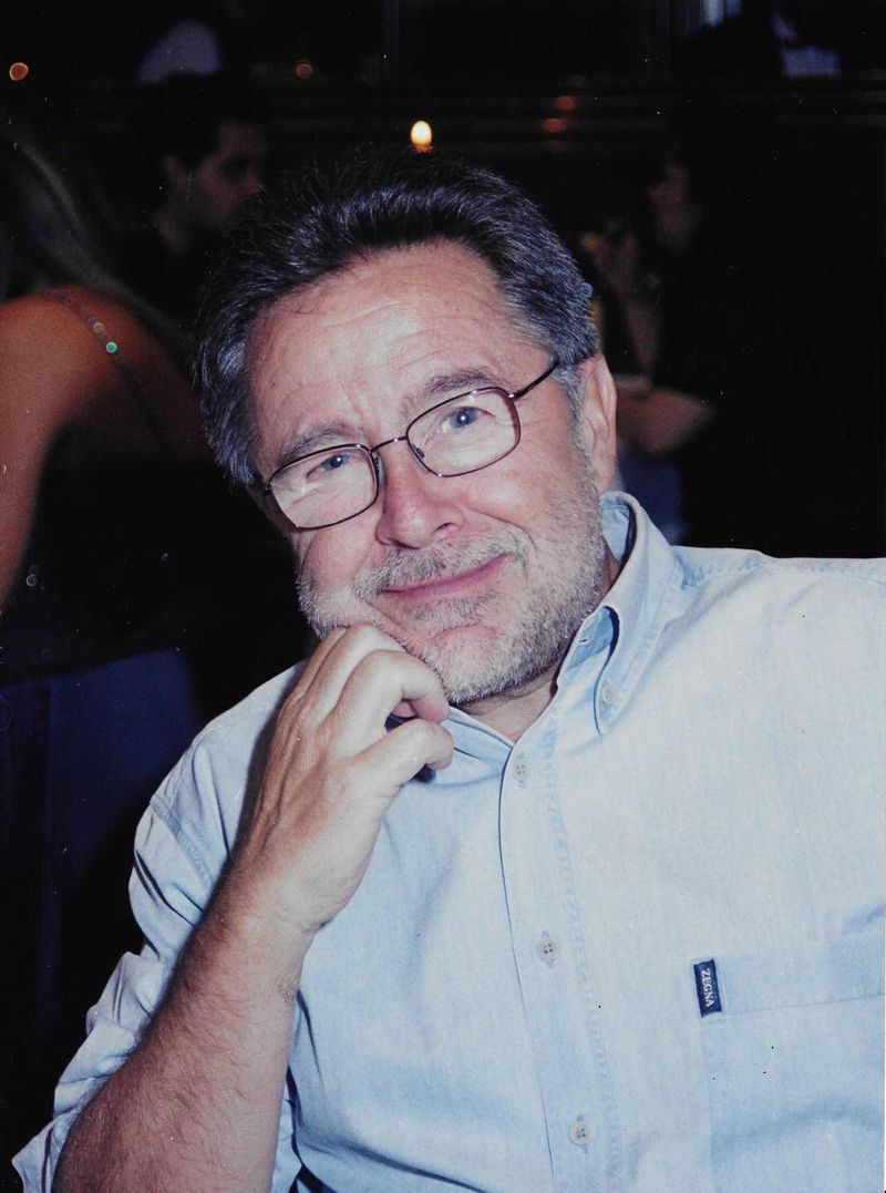 José Luis Gimeno Londres en la actualidad, con barba canosa y gafas, sonriendo con la mano en la barbilla