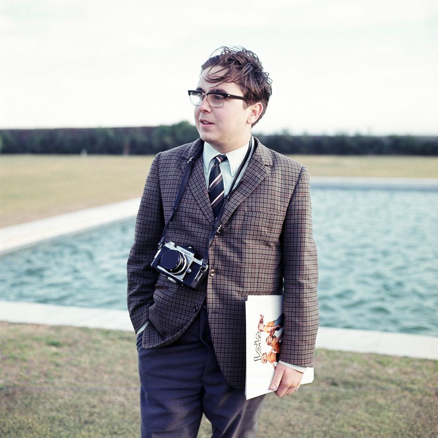 José Luis Gimeno en 1968 dirigiendo una sesión de fotos para Lois Jeans, con americana de cuadros, corbata, una cámara Nikon al cuello y bocetos bajo el brazo